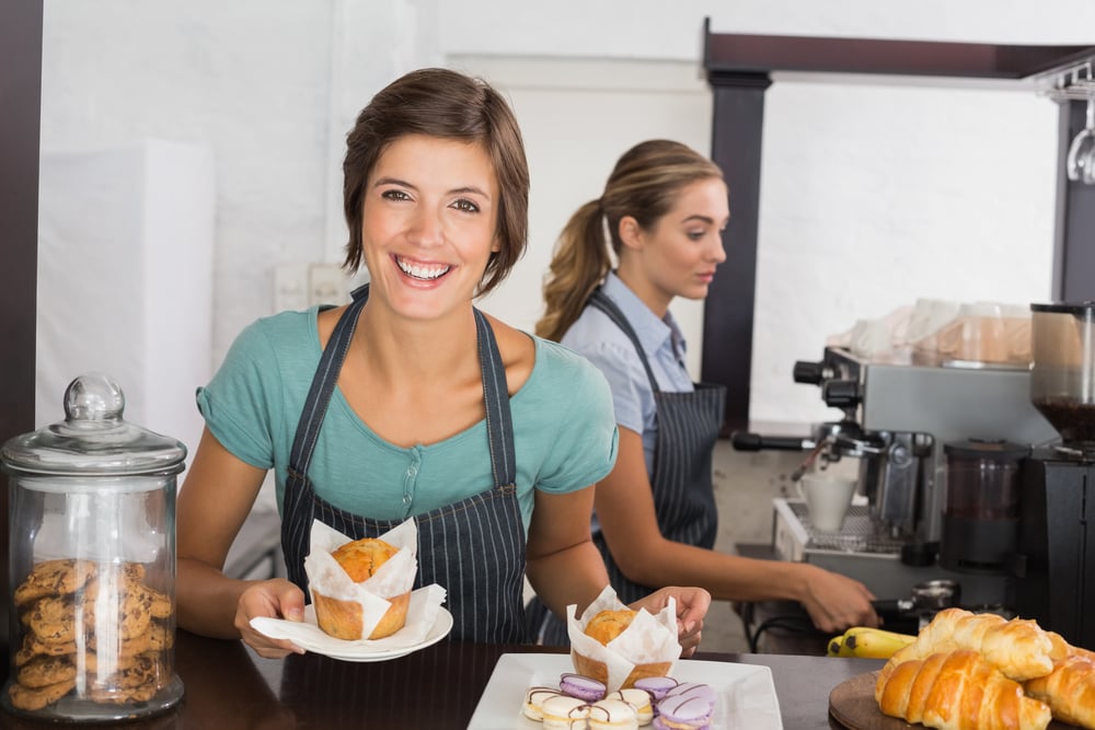 bakery owner carrying a muffin on a plate